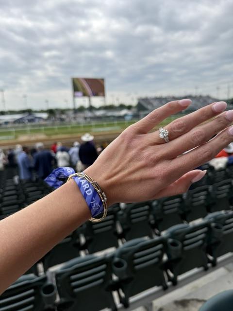 Stacked gold bracelets and engagement ring photographed at the Churchill Downs grandstand