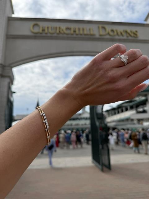 Engagement ring and stacked bracelets photographed beneath the Churchill Downs arch